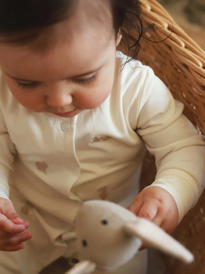Sleepsuit bunnies worn by baby playing with rattle toys
