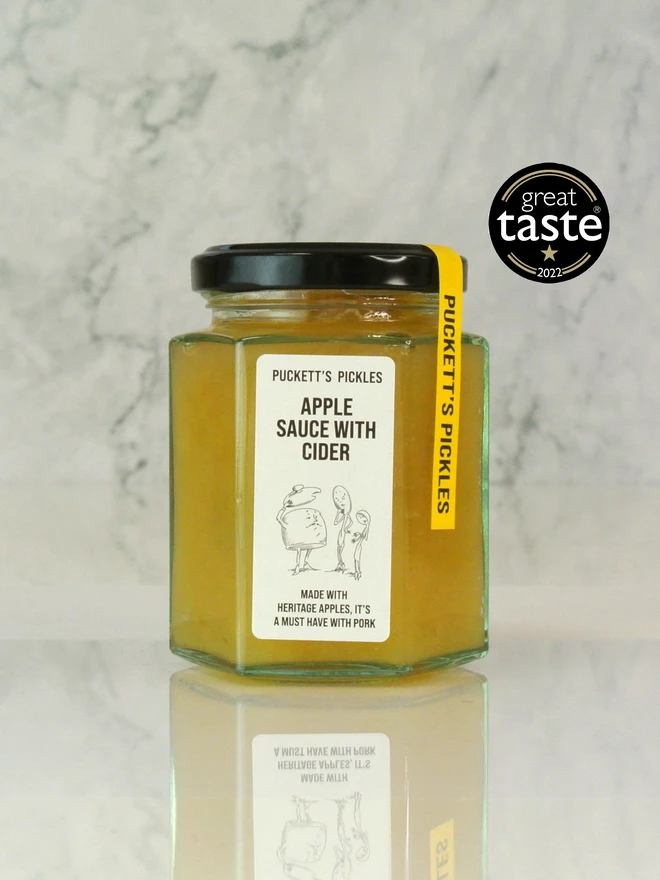 apple sauce with cider. a jar of apple sauce photographed against a marble background.