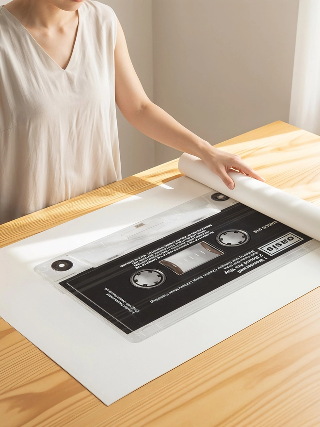 oasis wonderwall cassette tape print. print being unrolled on wooden table.