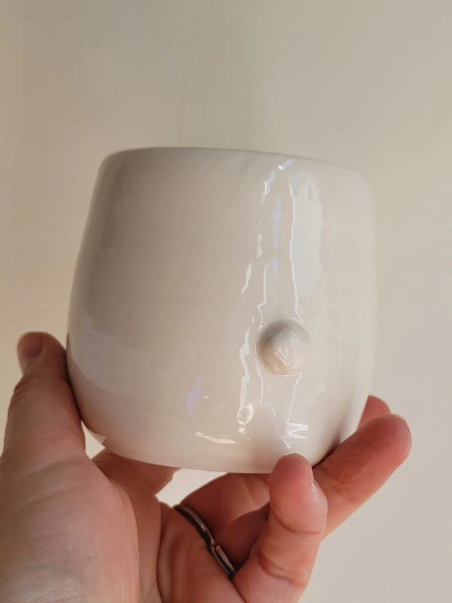 the back of a white ceramic tumbler cup showing the back with a white bunny rabbit tale