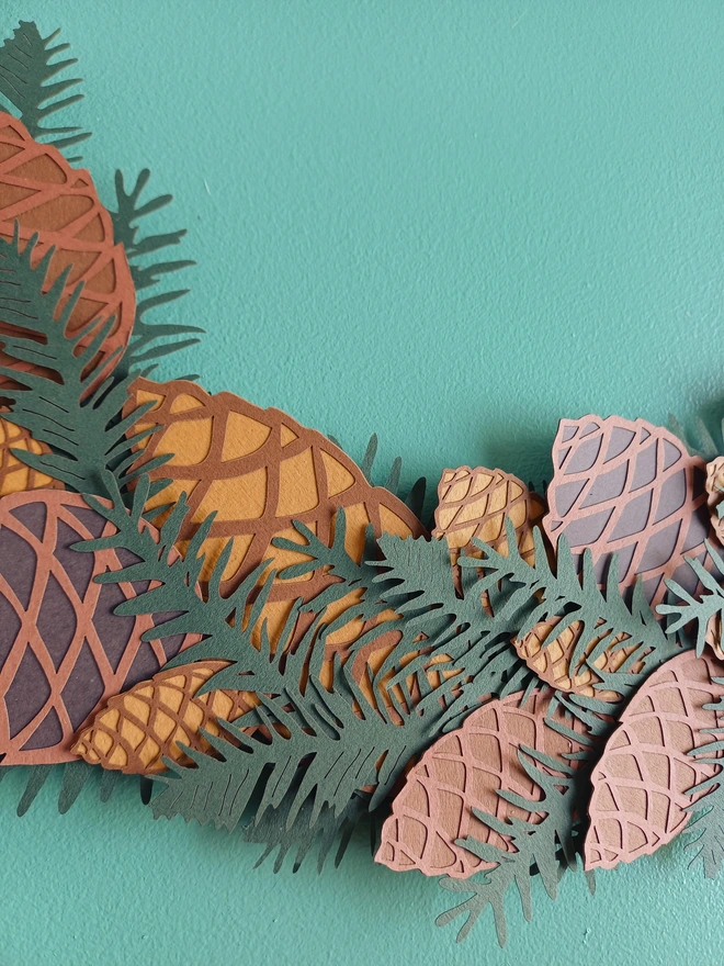 Close view of Papercut pinecone and spruce detail on everlasting wreath
