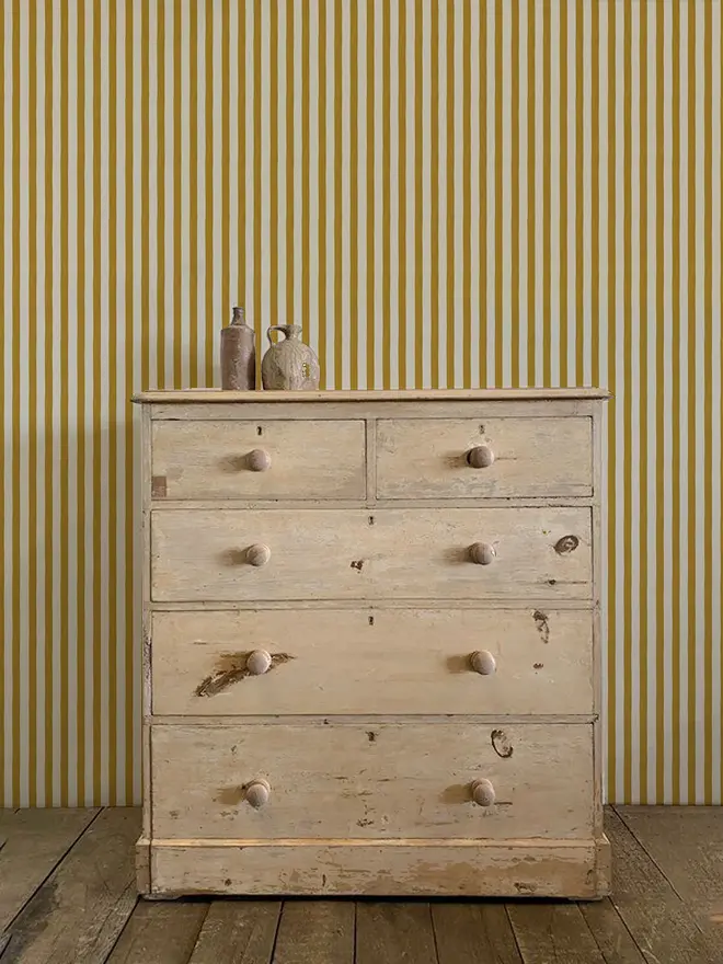 circus stripe painted wallpaper. mustard yellow and white striped wallpaper on a wall.
