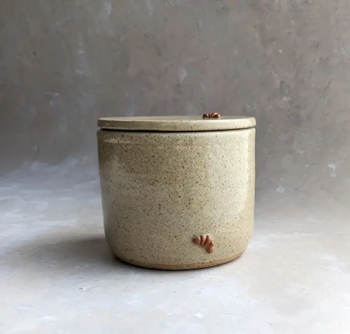 Croissant Butter Crock in biscuit glaze with a small croissant design on the front, set against a grey background.