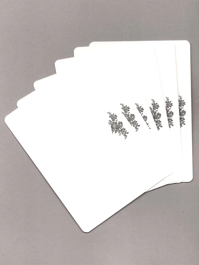 Six notecards with black flowers at the top laid out on a grey background 