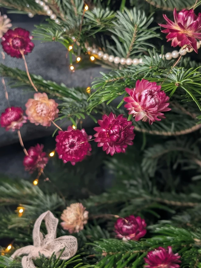festive dried flower bud garland. pink dried flower garland hung on christmas tree.