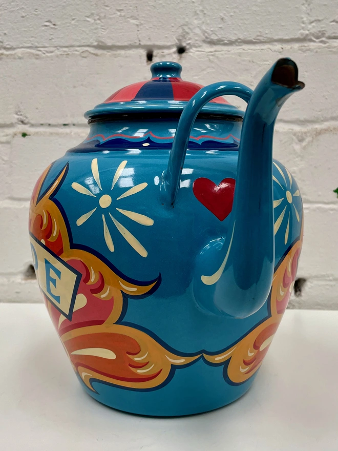 Large blue vintage enamel teapot, hand-painted with a traditional fairground inspired design in pink, yellow and orange. 'Hope' is painted in a banner across the centre.