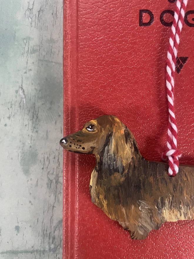 Long - Haired Dachshund Christmas Tree Decoration placed on a book about dogs