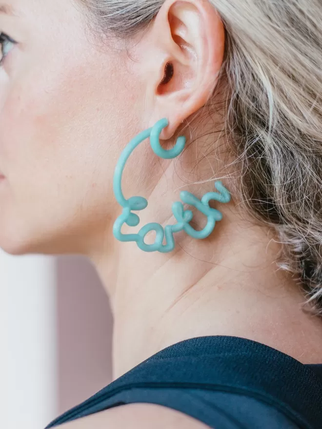 100% Recycled Ocean Plastic - 'Save' 'Earth' Hoop Earrings seen on a woman.