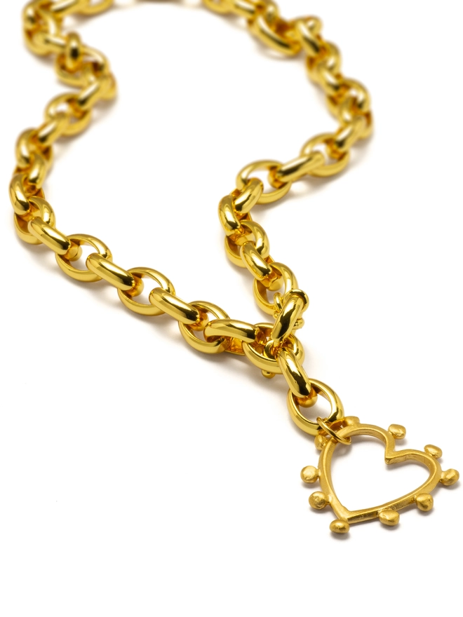 The Romeo Necklace is love, made bold. Featuring a chunky gold-plated front-fastening chain adorned with our large studded heart charm, this statement piece is designed to be seen. Strong, radiant, and effortlessly cool, it brings modern romance to everyday styling — perfect worn solo or layered for extra impact. A powerful symbol of confidence, connection, and standout style.