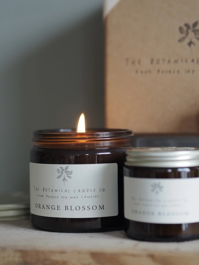 A warm glow from the lit Orange Blossom soy wax candle in a jar