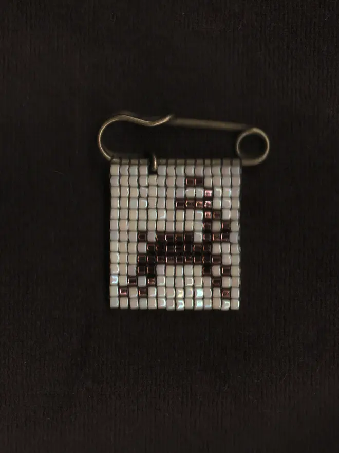 'creature i' tiled beaded rabbit pin. a beaded pin badge with a brown rabbit on a pearl background.