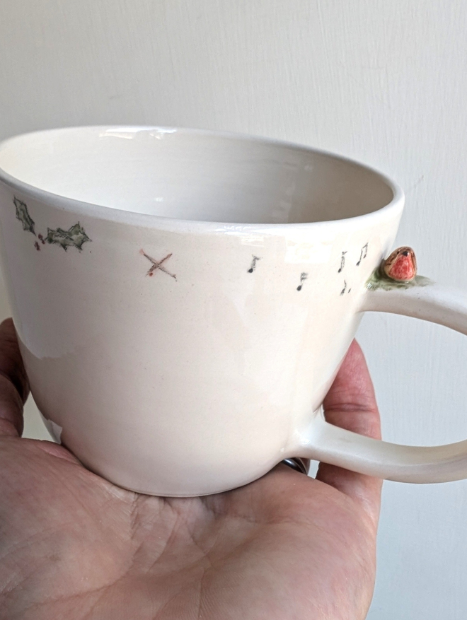 ceramic cup with a tiny pottery robin on the handle with musical notes hand painted christmas holly and tiny bird prints 