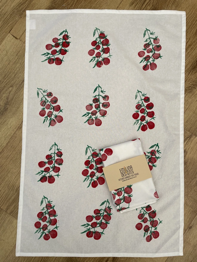 Tomatoes Kitchen Tea Towel. White fabric with a diagonal pattern of red tomatoes.