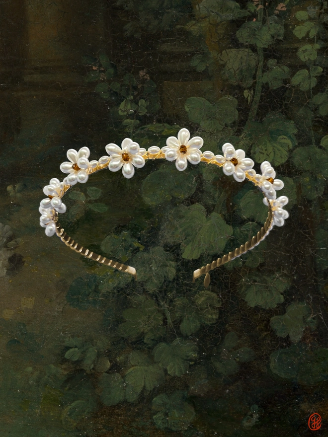 A gold headband adorned with a beaded daisy chain made with glass pearls and amber faceted glass beads.