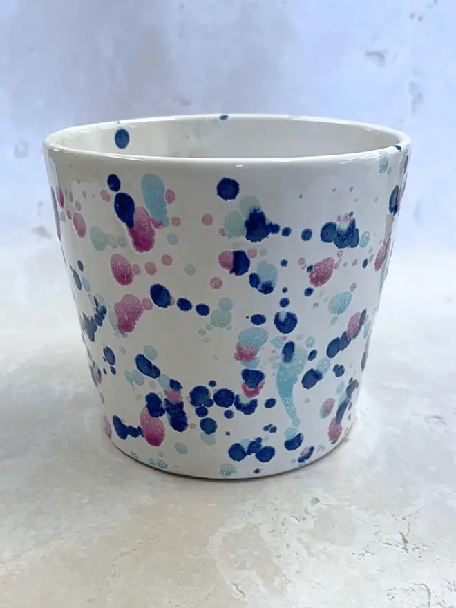 Sweetpea Large Pot, a colourful pot sitting on a stone surface in front of a plain background.