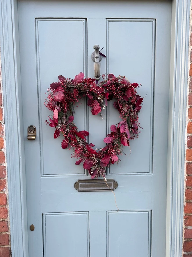 Dried Woodland Pink Heart Wreath hanging on a grey door