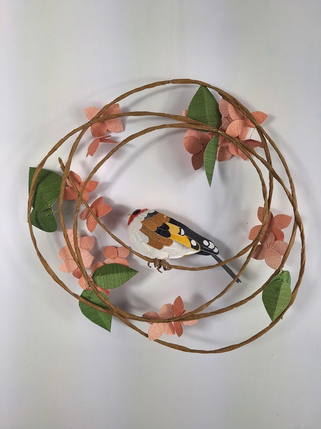 back view of a wall sculpture featuring a goldfinch on a spring wreath of peach hydrangea