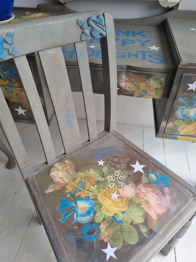 Vintage painted dressing table and chair. Painted in coffee grey and decorated using layered antique florals with yellow and blue accents and finished with hand-cut white paper stars. Text reads in blue 'think happy thoughts'. Heavily distressed finish.