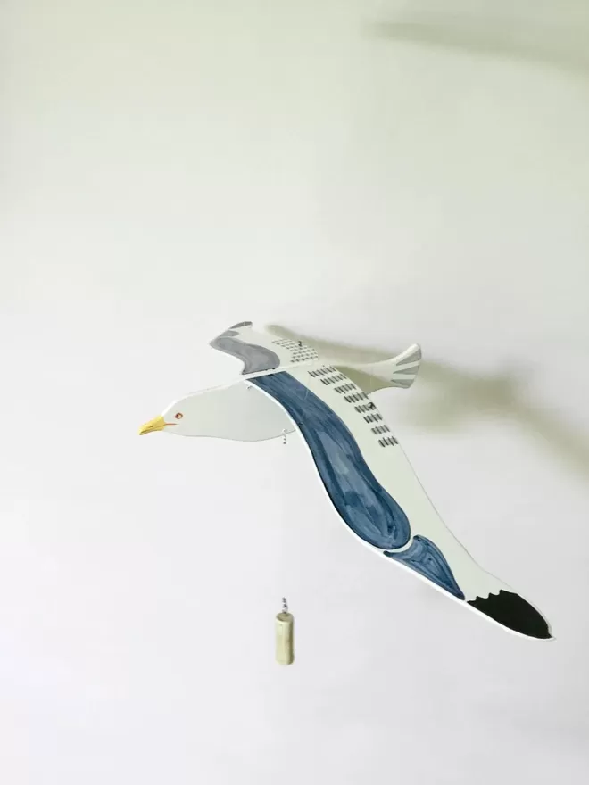 Flying wooden seagull hanging from ceiling against a white wall 