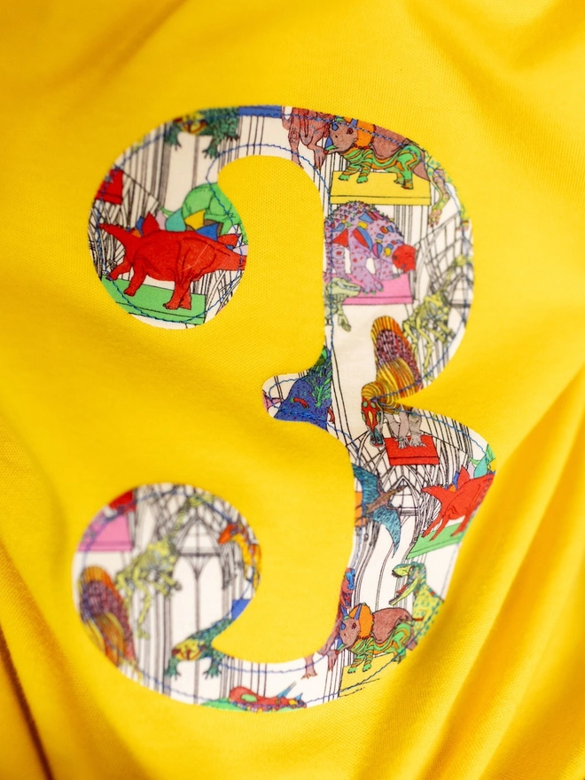  a yellow t-shirt with a number 3 in a liberty dinosaur print on front