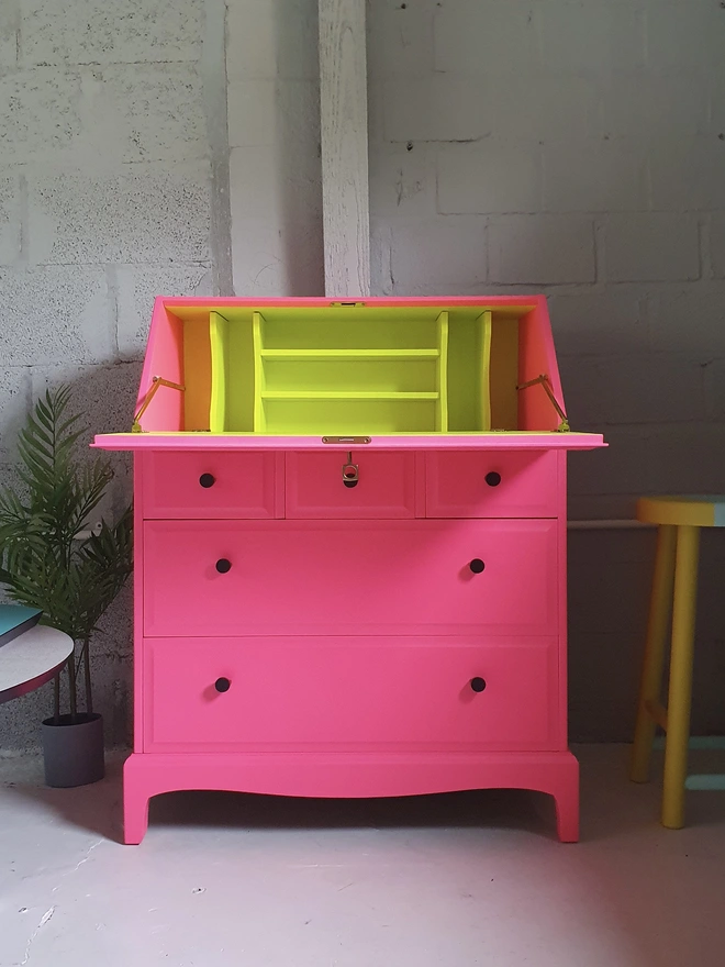 Neon pink and yellow refinished vintage bureau desk from the front with the lid open