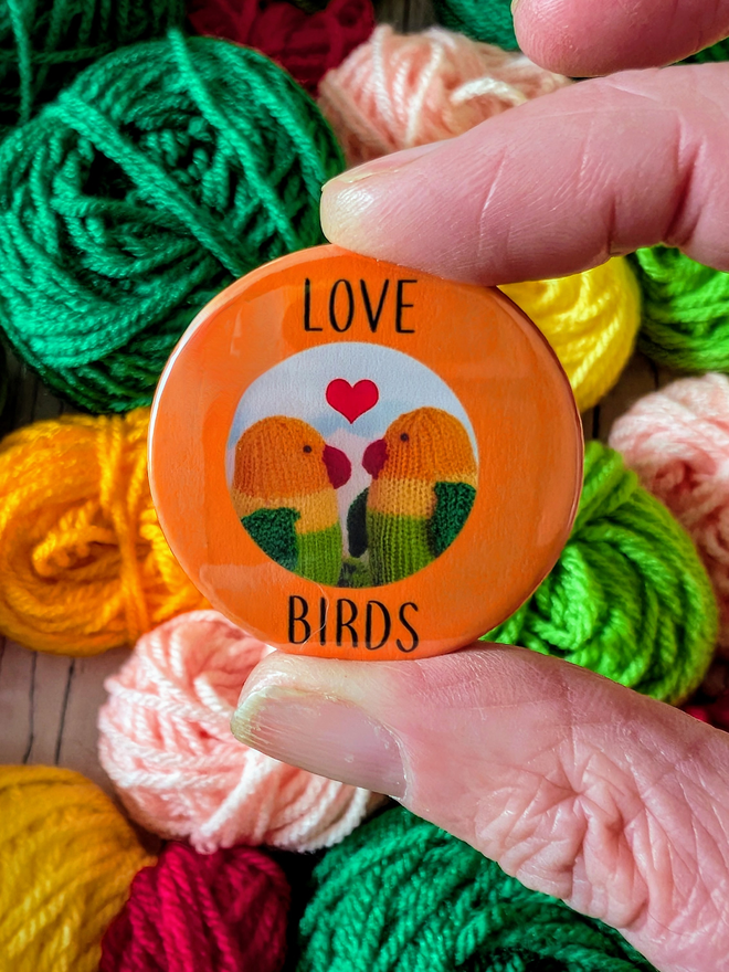 orange badge with the words Love Birds and a photo of knitted lovebirds on it