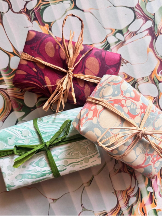 Set of 3 Wrapped Soaps. A selection of three soaps wrapped in multicoloured paper, tied with twine.