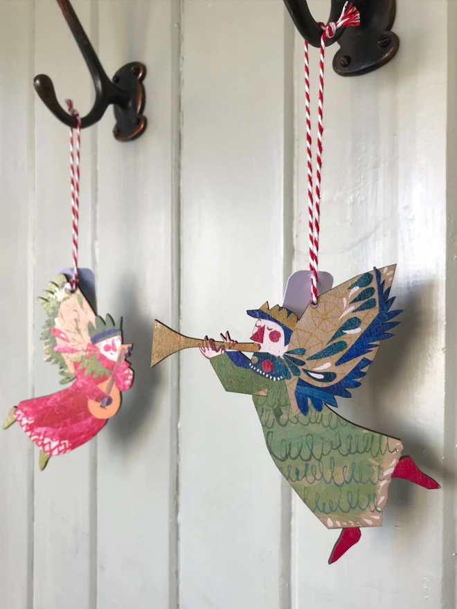 Red and green illustrated angel decorations by Esther Kent, hangs from red and whte striped string