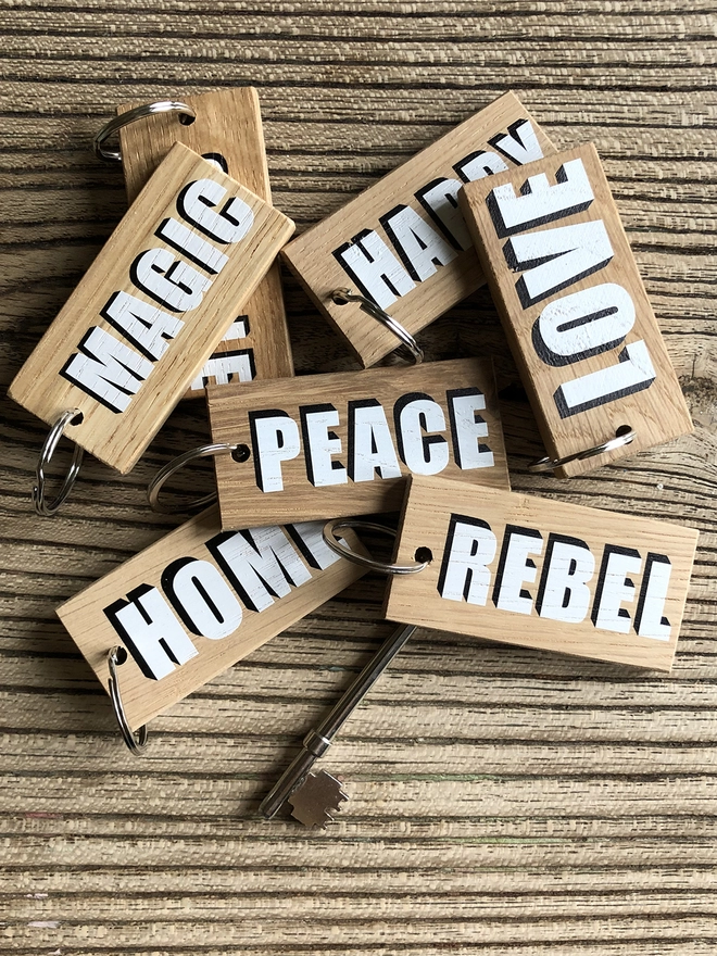 A close up of a bunch of wooden keyrings with bold white and black words  