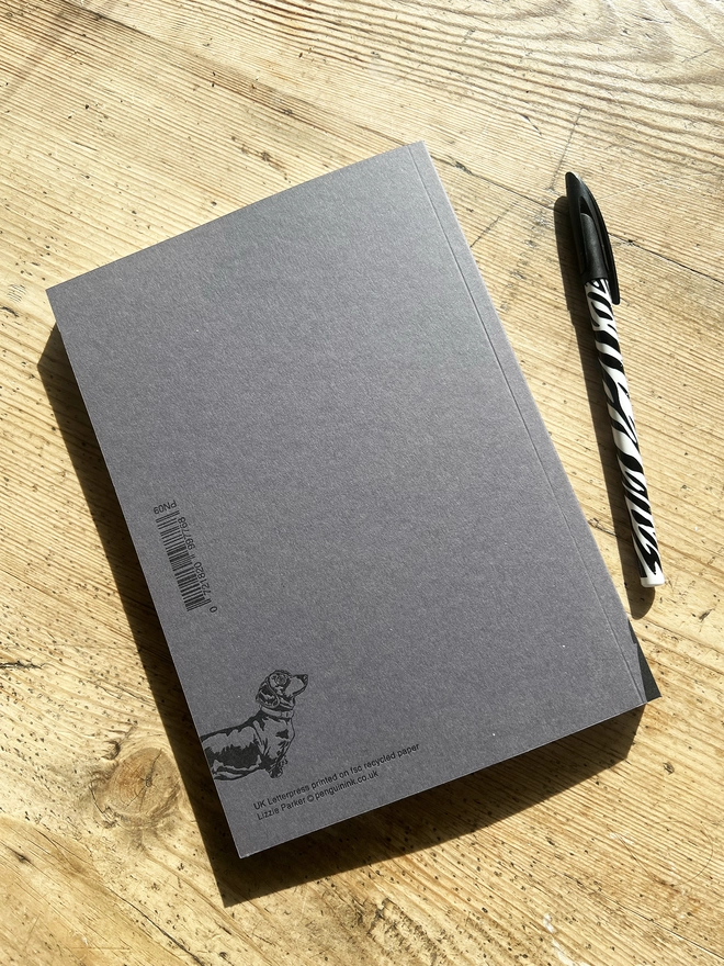 Back of the note book with a puppy Dachshund in the bottom left hand corner.