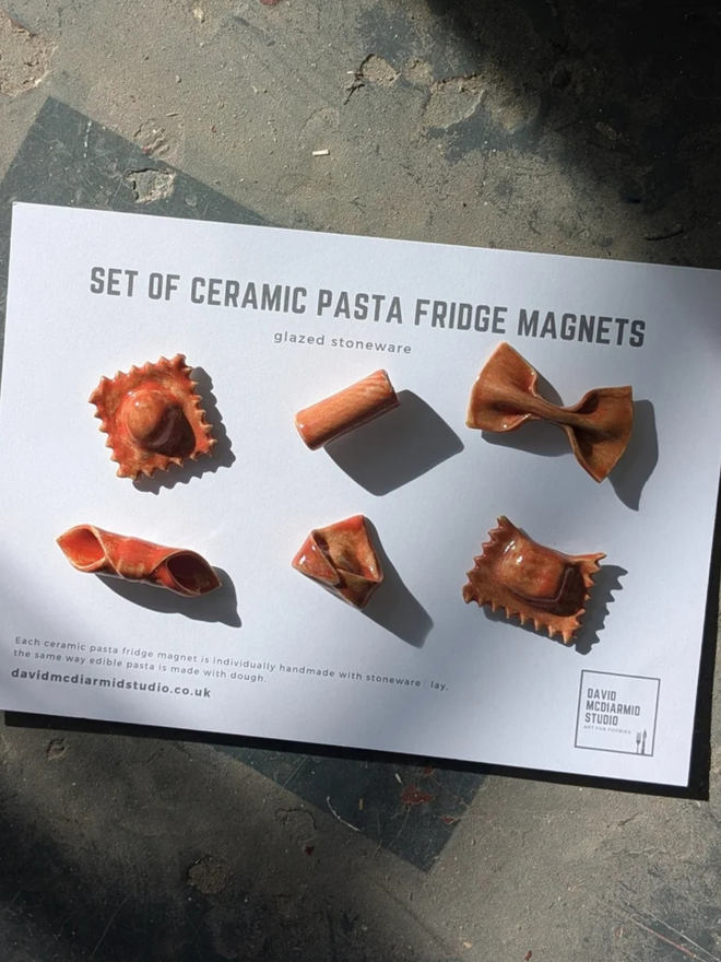ceramic pasta magnets (set of 6). six red glazed pasta magnets on a paper backing.