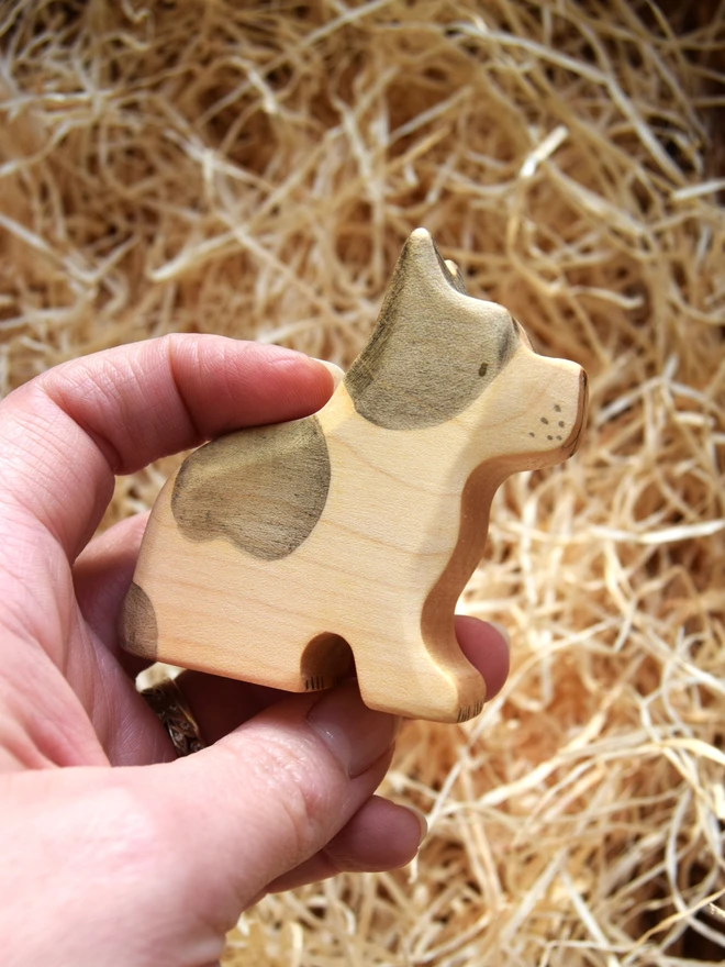 french bulldog wooden toy being held above woodwool