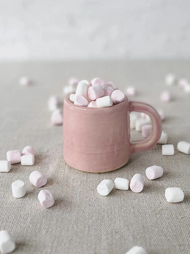 Classic Ceramic Espresso Mug, a colourful ceramic espresso mug sitting on a plain surface against a white backdrop. It is accompanied by a group of marshmallows. 
