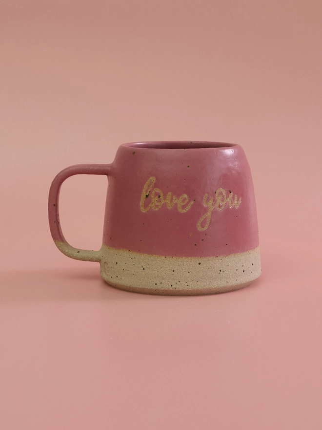 ceramic mug with writing saying Love You in a bright pink glaze, made with a fleck stoneware clay