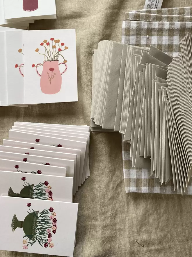 selection of greetings cards ready to be packed up with envelopes on gingham tablecloth. 