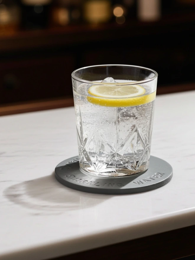 a cut glass tumbler on a hand painted leather coaster