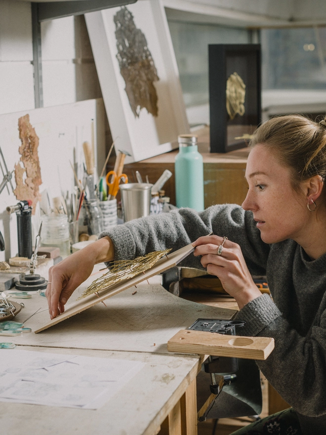 Holly checking the lie of the metal landscape on a template sheet of wood