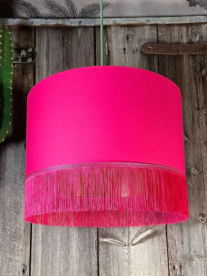 Pomegranate Pink Lampshade With Gold Lining & Pink Fringing, hanging. 