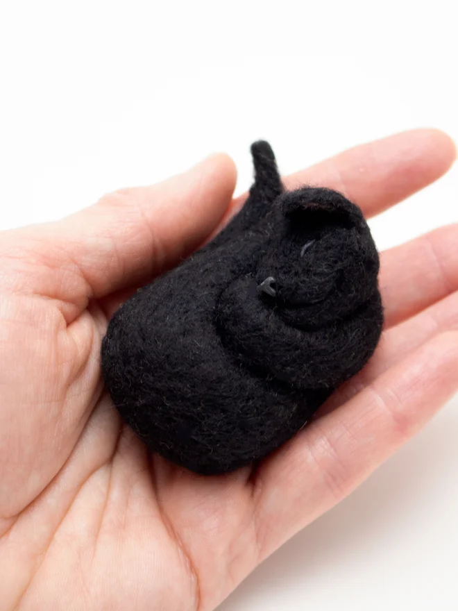 A handmade needle felted sleeping black cat brooch. Made by artist Laura Cronin, aka Bumble & Earwig