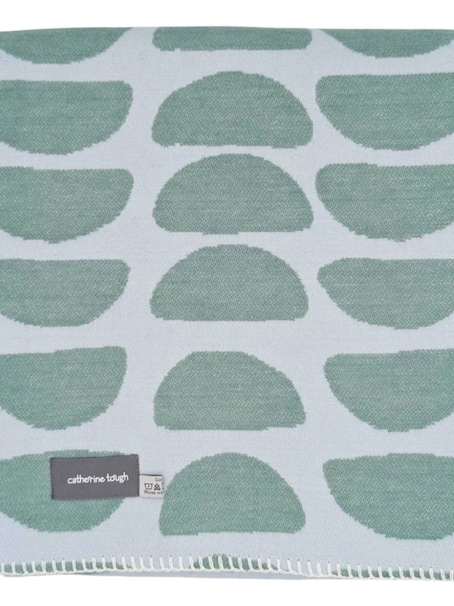 Organic Cotton Throw, a cotton throw folded into a square on a floor. 