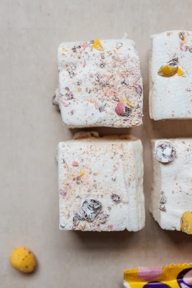 Mini Eggs Jumbo Marshmallows four pack on a marble table top with crushed mini eggs scattered around