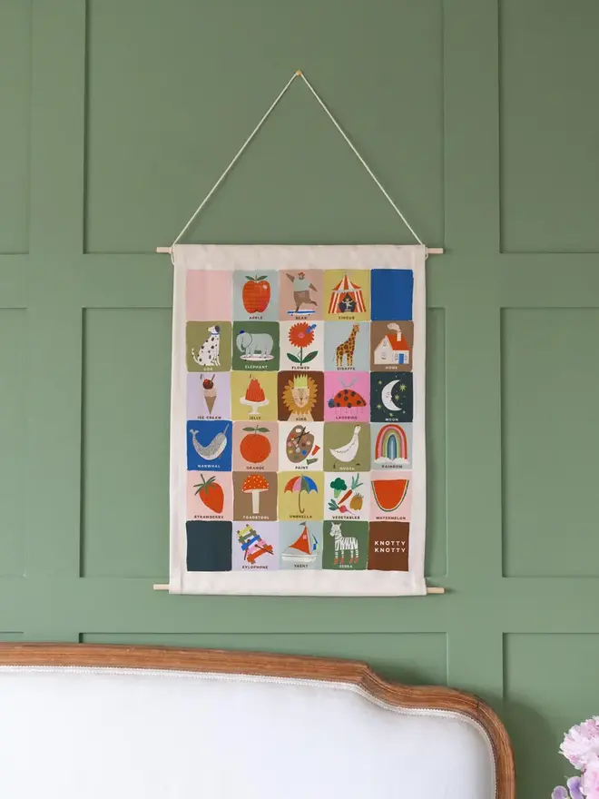 Colourful Rainbow Alphabet Fabric Banner, hanging on a green wall. 
