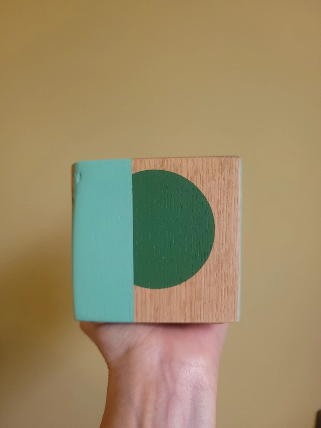 Wooden cube tealight holder painted with a green and mint P on a yellow background