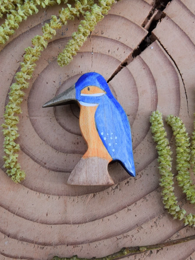 wooden toy kingfisher on wood slice with catkins