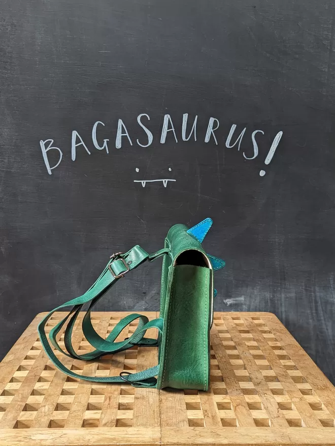 Side view of green leather 'Bagasaurus' backpack with turquoise spikes.