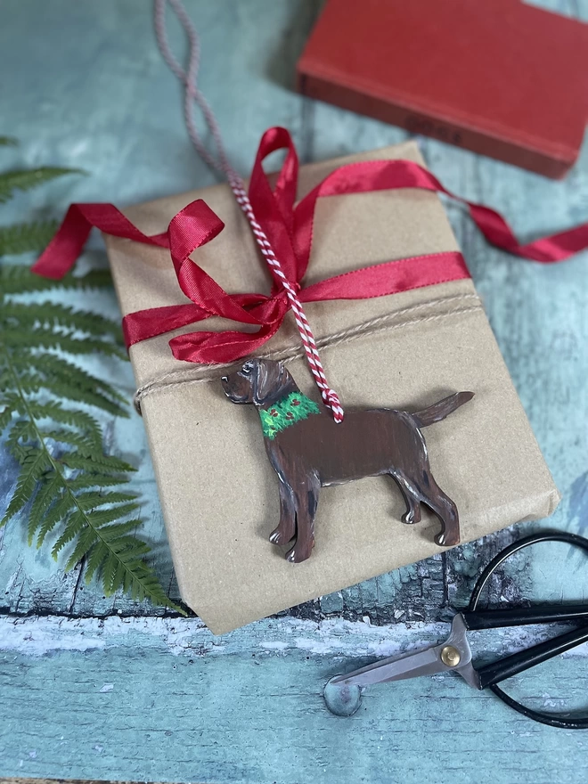 A Chocolate Labrador Christmas decoration placed on a wrapped gift