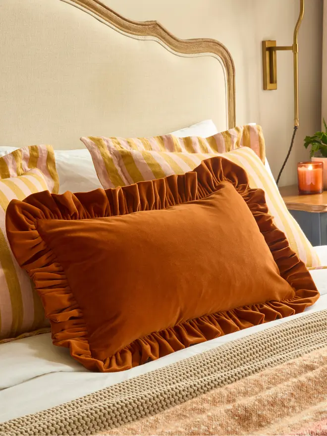 Handmade peach and mustard stripe linen oxford cushion styled with velvet cushion on bed, Kika Bespoke