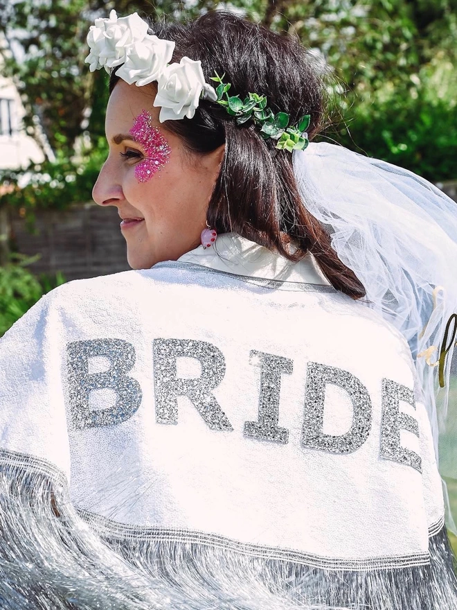 A woman wearing the gretna bride cape at her hen party. She is wearing a viel and has glitter face paint.