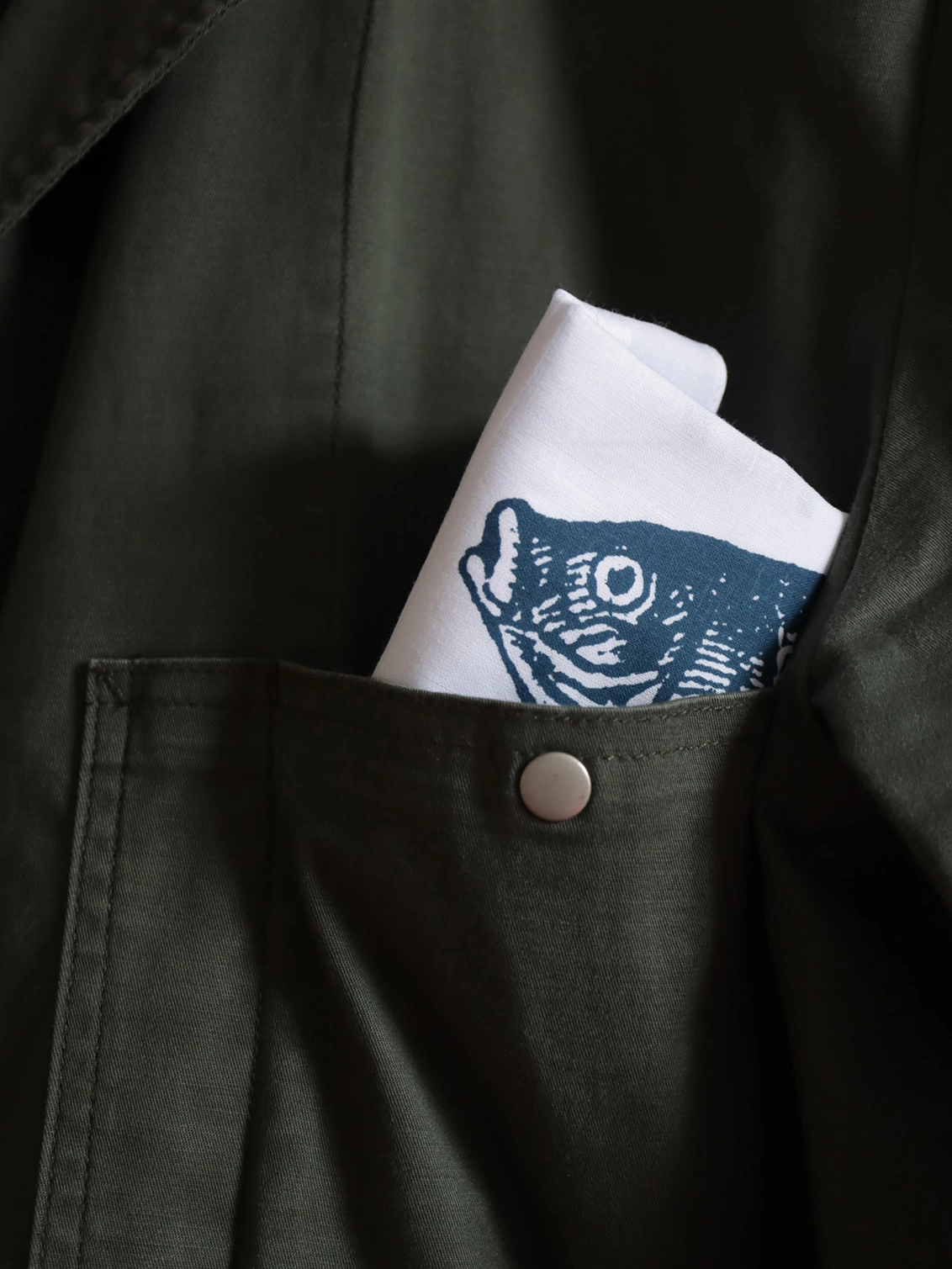 A Mr.PS Fisher hankie tucked in the top pocket of a dark green jacket