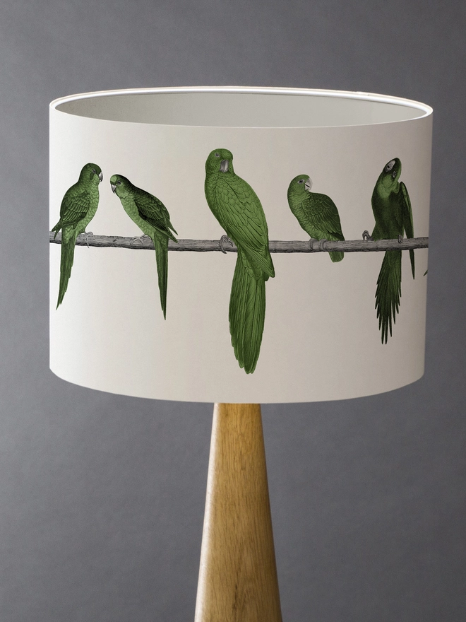 A colourful lampshade featuring a lively group of green parrots in a tropical jungle-inspired design, bringing a playful touch to home interiors.